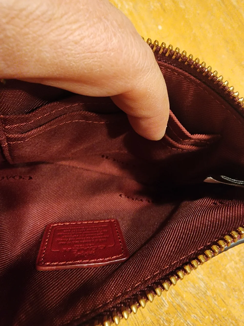 red polished pebble leather Coach wristlet, featuring gold-tone hardware